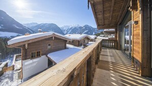 A wooden chalet with a balcony overlooking a snowy mountain landscape. - Wellness Chalet near Wildkogel (Neukirchen)