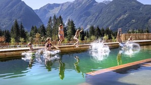 Una piscina con gente saltando, rodeada de montañas.