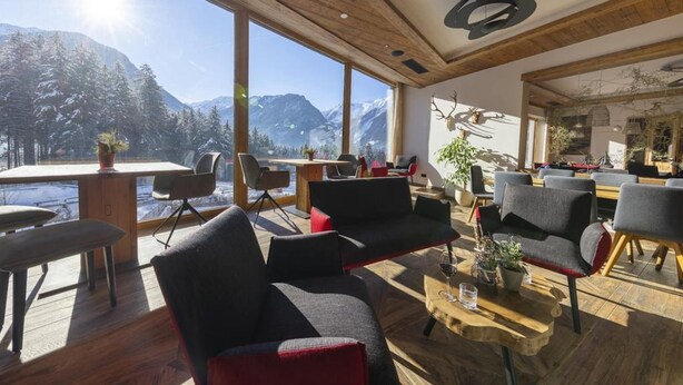 Un interior moderno con techo de madera, ventanas amplias con vistas a la montaña y una variedad de opciones de asientos.