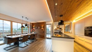 A modern kitchen with a central island, wooden flooring, and pendant lighting.