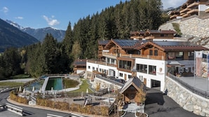 A mountain lodge with multiple wooden buildings, a swimming pool, and a stone retaining wall.