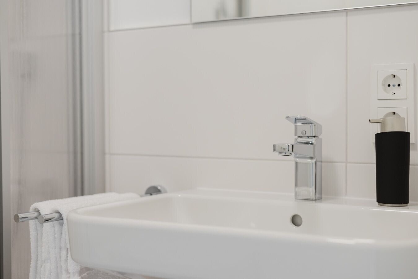 Une salle de bain avec un lavabo blanc, un miroir et un porte-serviettes.