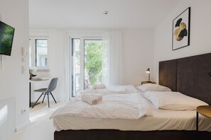 A modern hotel room with a large bed, a desk, and a chair.