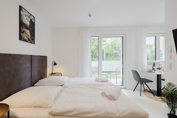 Une chambre moderne avec un grand lit, un bureau et une vue sur l’extérieur.