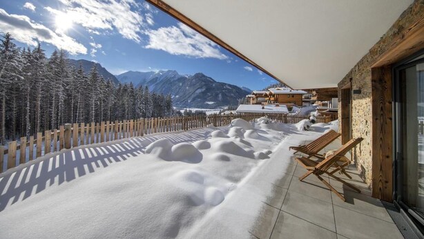 Un balcon offrant une vue sur des montagnes et des arbres couverts de neige.