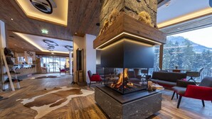 A modern interior with a fireplace, wooden flooring, and a view of snow-covered mountains. - Chalet with sauna, Neukirchen (Neukirchen)