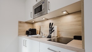 A modern kitchen with a built-in microwave, a coffee machine, and a knife block. - The InnSight - Apartmenthouse (Passau)
