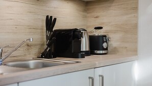 Une cuisine avec un revêtement mural en bois, une machine à café, un grille-pain et un évier.