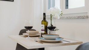A dining table with two wine glasses, a bottle of wine, a vase with white flowers, and plates. - The InnSight - Apartment house (Passau)