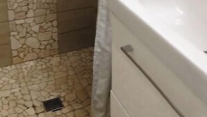 A bathroom with a stone-patterned wall, a shower curtain, and a white vanity with drawers.