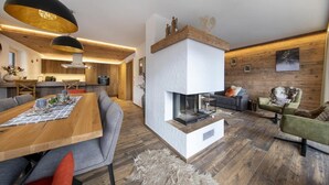 Ein modernes Wohnzimmer mit Kamin, Holzboden und zeitgemäßen Möbeln.