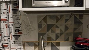 A kitchen with a built-in toaster oven, a stainless steel sink, and a microwave.