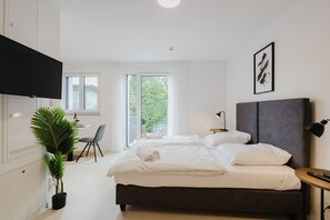 Une chambre moderne avec un grand lit, un bureau et une télévision.