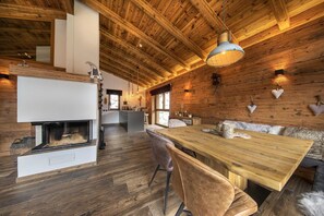 A spacious room with a large wooden dining table, a fireplace, and a cozy seating area.