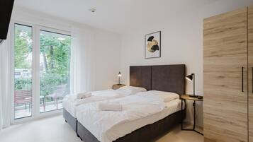 Een moderne slaapkamer met een groot bed, een houten garderobe en een balkon met zitplaatsen.