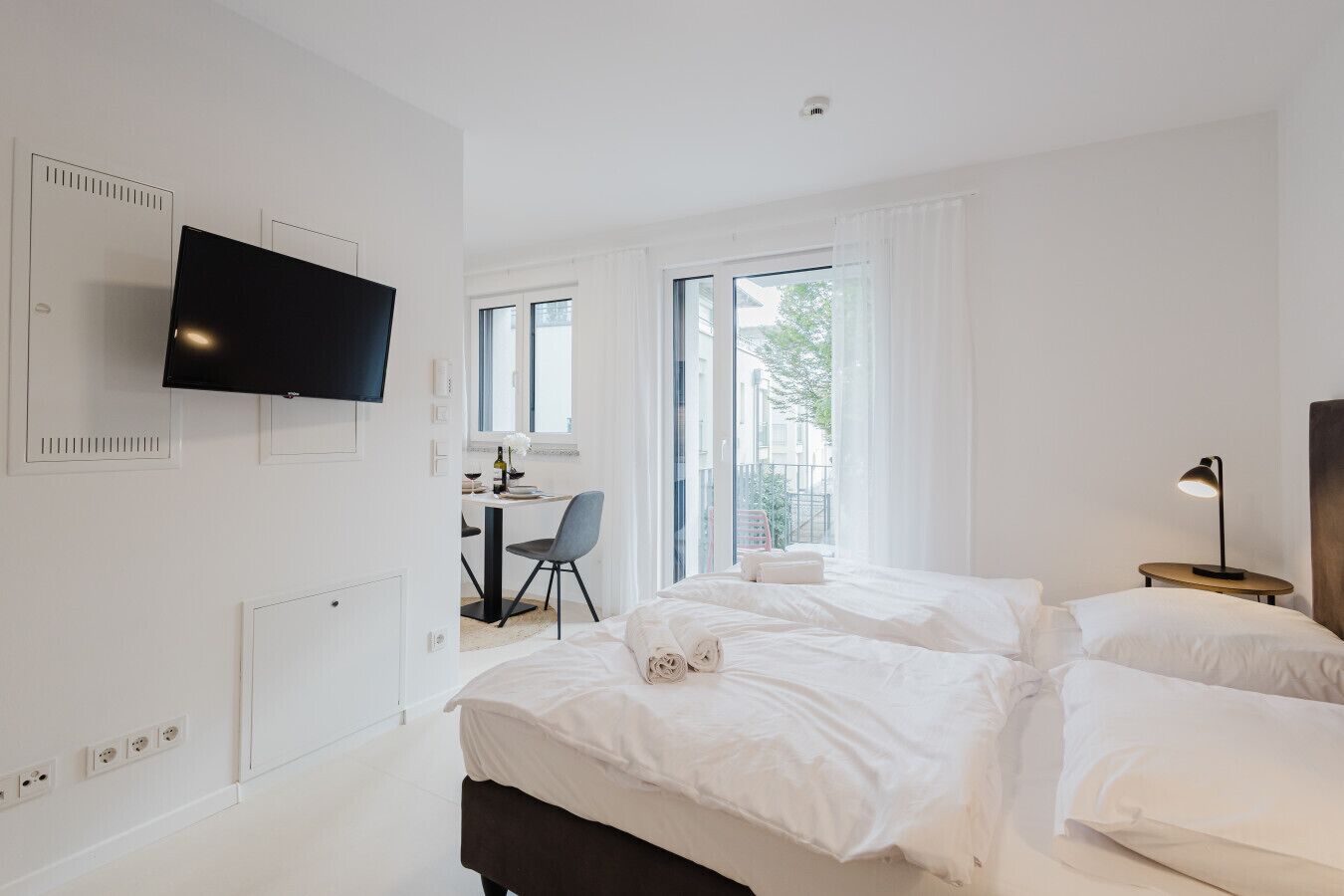 A modern hotel room with a bed, a desk, and a TV.