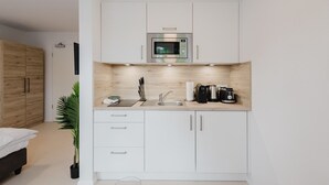 A compact kitchenette with a microwave, coffee maker, and sink. - The InnSight - Apartmenthouse (Passau)