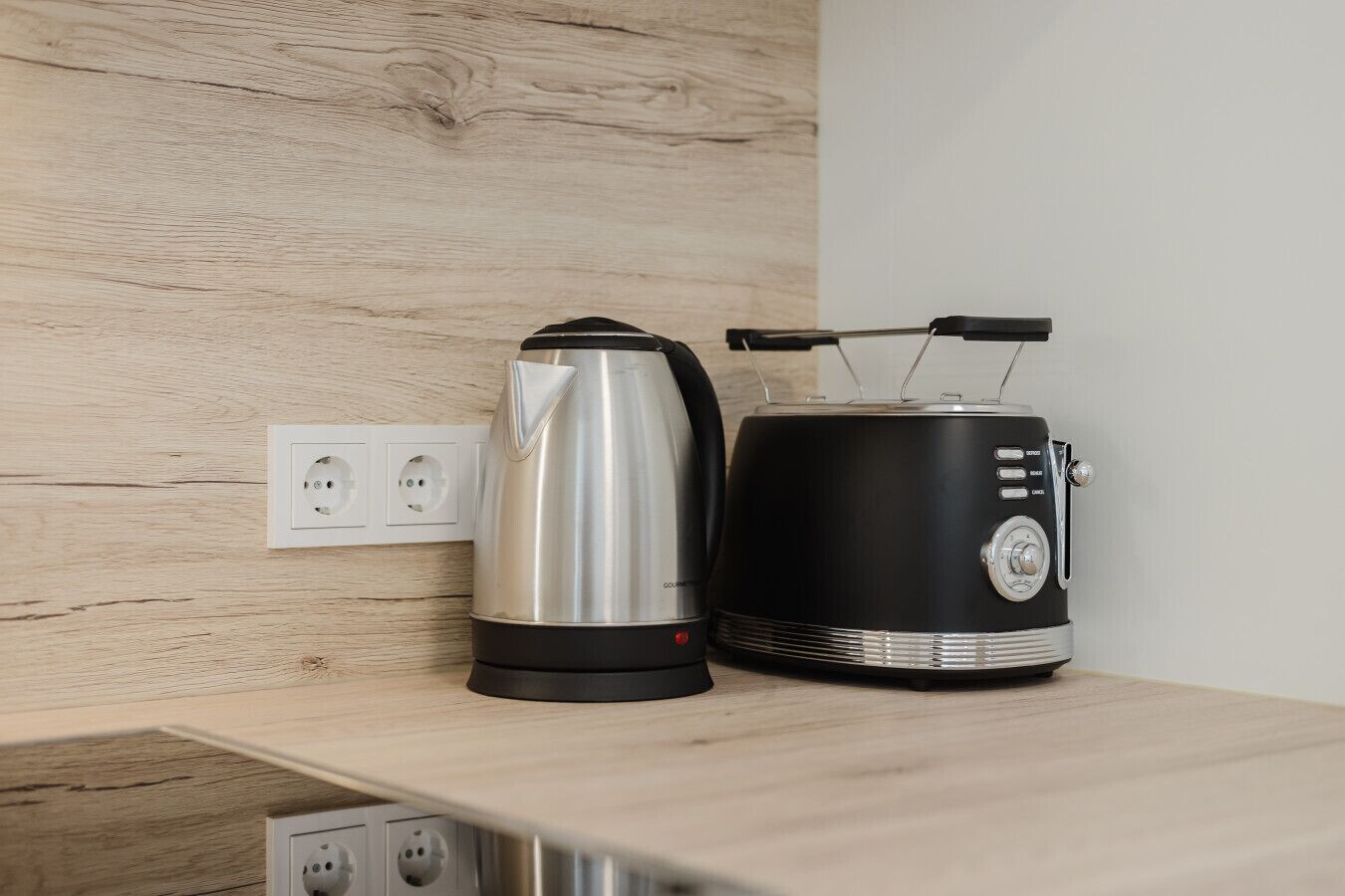 A kitchen counter with a kettle and a toaster.