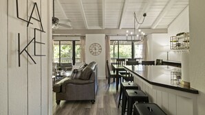 A spacious kitchen with a central island, a dining area with a high table and chairs, and a cozy seating area with a sofa and chairs. - Lake Escape w/ Deck & Patio (Horseshoe Bay)