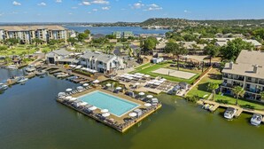 An aerial view of a waterfront property with a central swimming pool, multiple boat docks, and surrounding residential buildings. - Lake Escape w/ Deck & Patio (Horseshoe Bay)