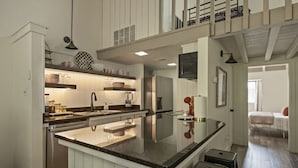 A modern kitchen with a central island, white cabinetry, and a dining area with a high ceiling and exposed beams. - Lake Escape w/ Deck & Patio (Horseshoe Bay)