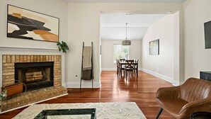 A living room with a fireplace, a dining area, and a hallway leading to another room. - Charming Round Rock Retreat (Round Rock)