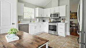 A modern kitchen with white cabinets, a stainless steel oven, and a microwave. - Charming Round Rock Retreat (Round Rock)