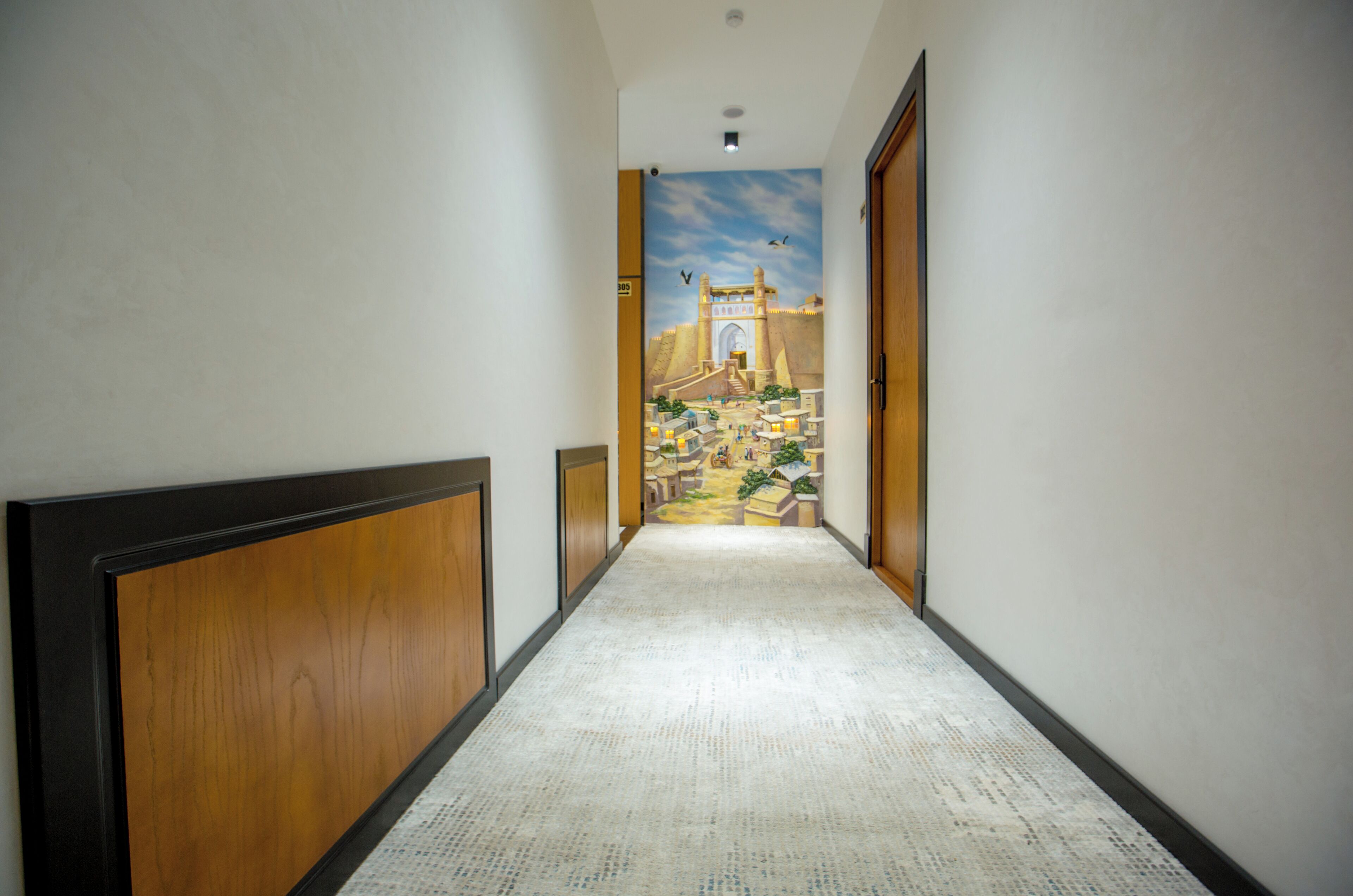 A hallway with a carpeted floor, wooden paneling on the walls, and a mural depicting a historical scene.