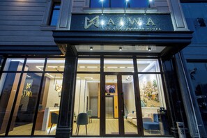 The exterior of the AJWA Plaza Premium Hotel with a modern facade, large glass windows, and a visible reception area inside. - Ajwa Plaza Premium Hotel (Bukhara)