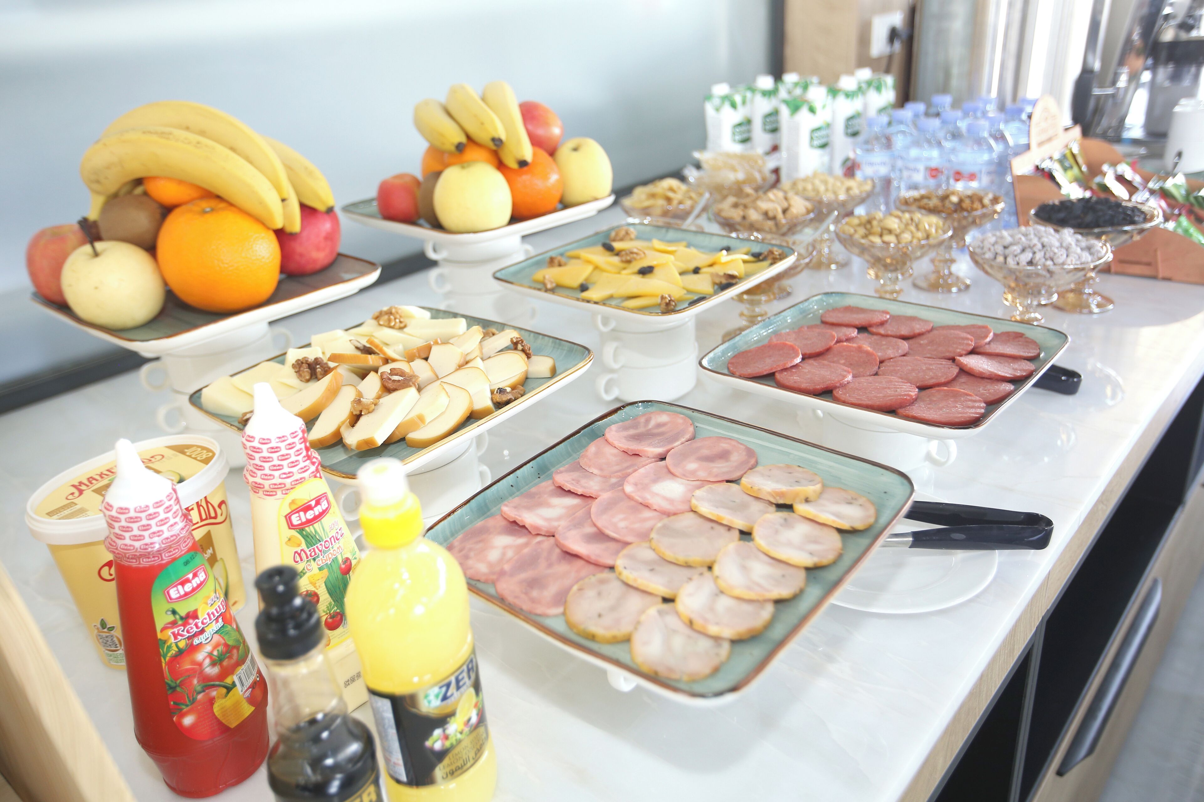 A buffet with various food items including fruits, cheeses, meats, and condiments.