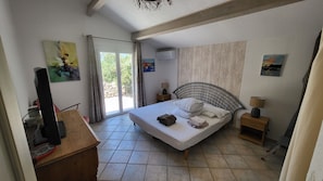 Un dormitorio con cama, escritorio, televisor y obras de arte en las paredes.