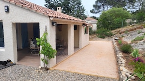 Una casa con porche techado, mobiliario exterior y camino de entrada de grava.