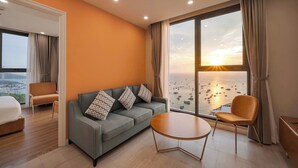 Et moderne hotelværelse med et stort vindue, en sofa, et rundt bord og en seng.