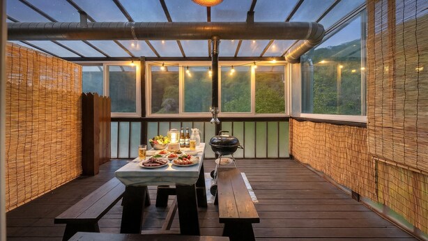 Eine Terrasse im Freien mit Esstisch, Grill und Lichterkette.