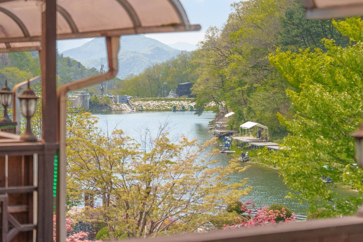 Vista del río con un pabellón, barcos y un puente.