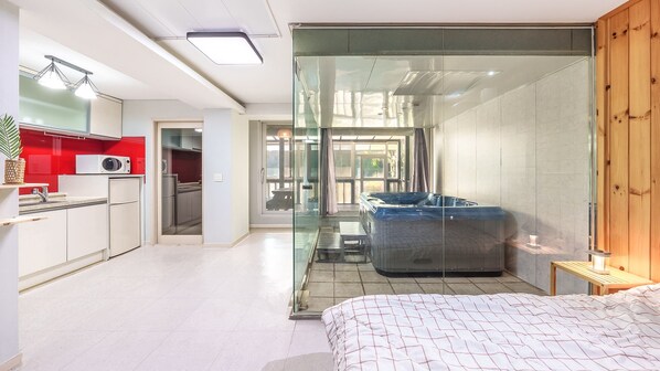 Un apartamento moderno con cocina, baño con paredes de vidrio y un dormitorio.