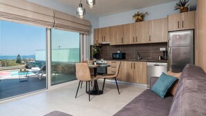 A modern kitchen with wooden cabinets, a stainless steel refrigerator, and a dining area with a table and chairs. - La Mer de Crete Suite private pool & sea view (Agia Pelagia)