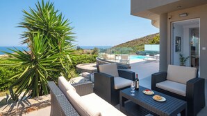 A terrace with wicker furniture, a pool, and a view of the sea. - La Mer de Crete Suite private pool & sea view (Agia Pelagia)