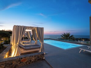 A poolside area with a pergola and lounge chairs, overlooking a body of water. - Villa La mer de Crete - private pool & sew view (Agia Pelagia)