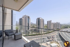 A balcony with a view of high-rise buildings and a busy highway.