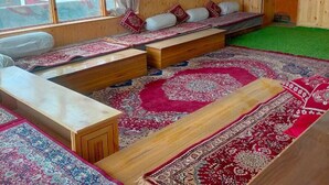A room with a large window, a sofa, a wooden bench, and a rug. - Kapoor Resort Kaza by Mountain Bee (Kaza)