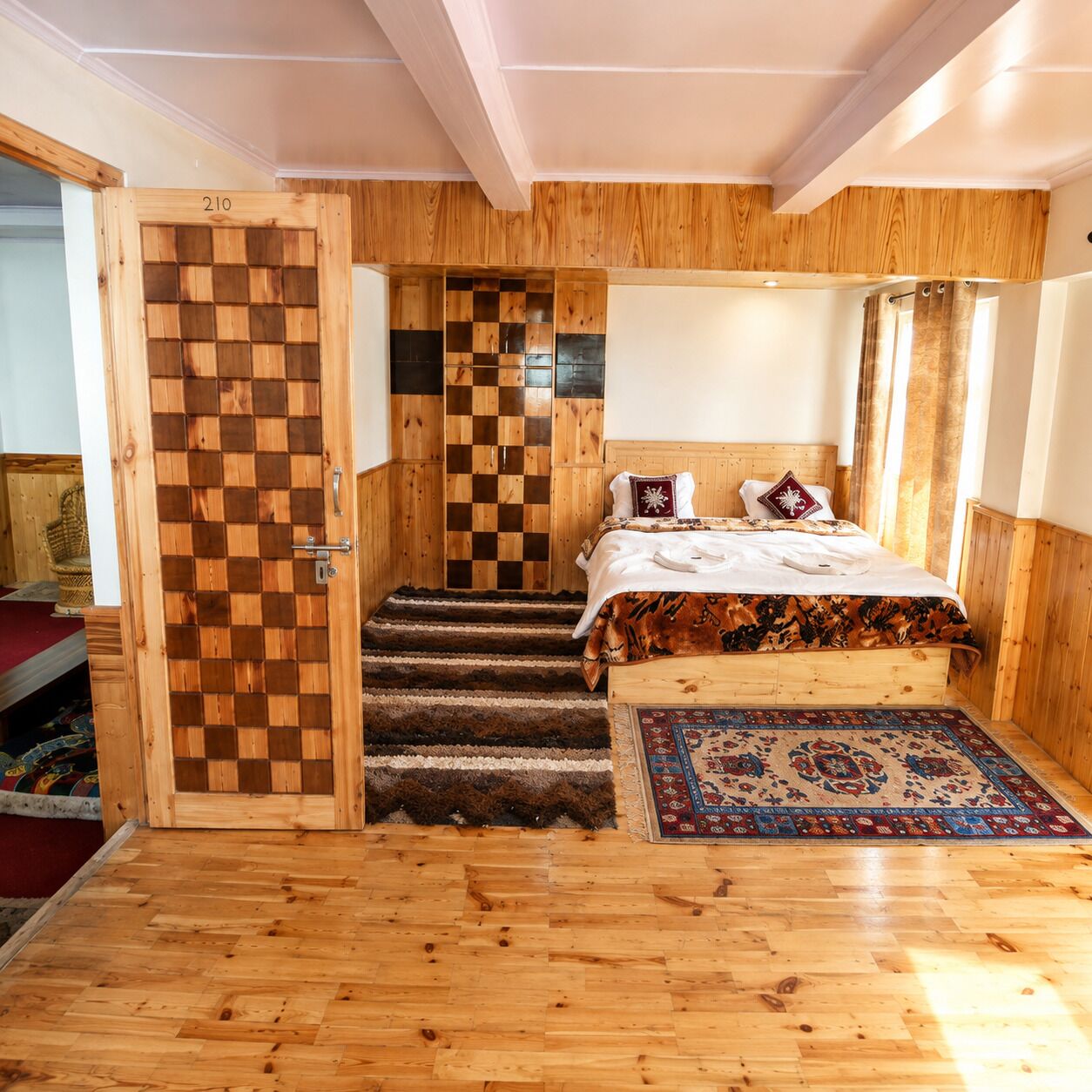 Un dormitorio con pared de madera a cuadros, cama con colcha estampada y piso alfombrado.