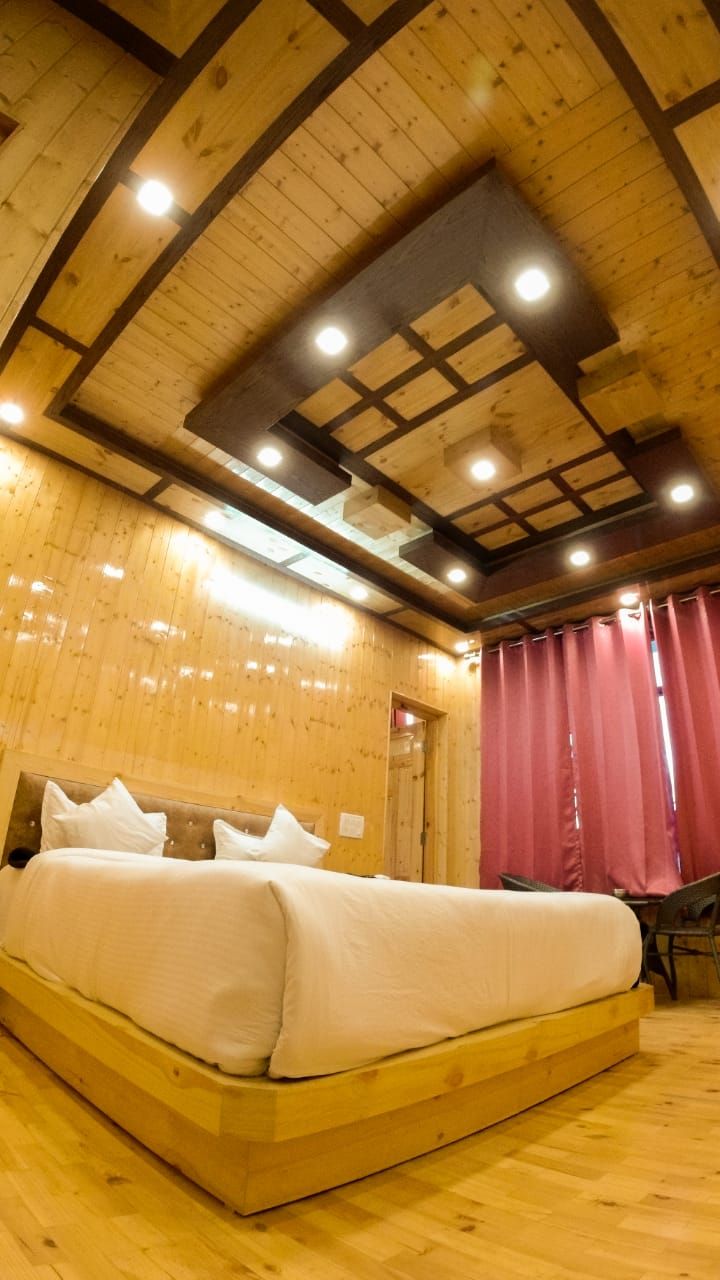 A wooden room with a bed, a chair, and a red curtain.