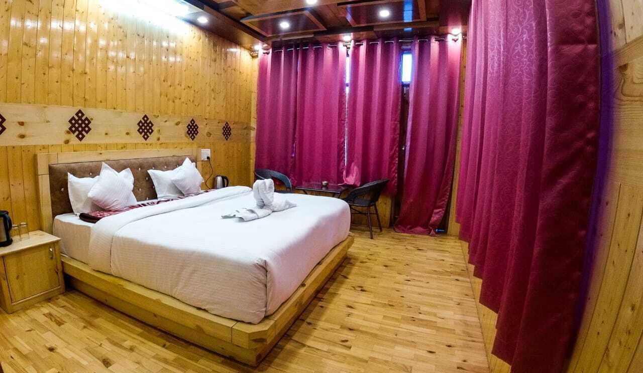 Una habitación con paneles de madera, una cama, una mesita de noche, una silla y una mesa.