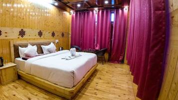 Una habitación con paneles de madera, una cama, una mesita de noche, una silla y una mesa.