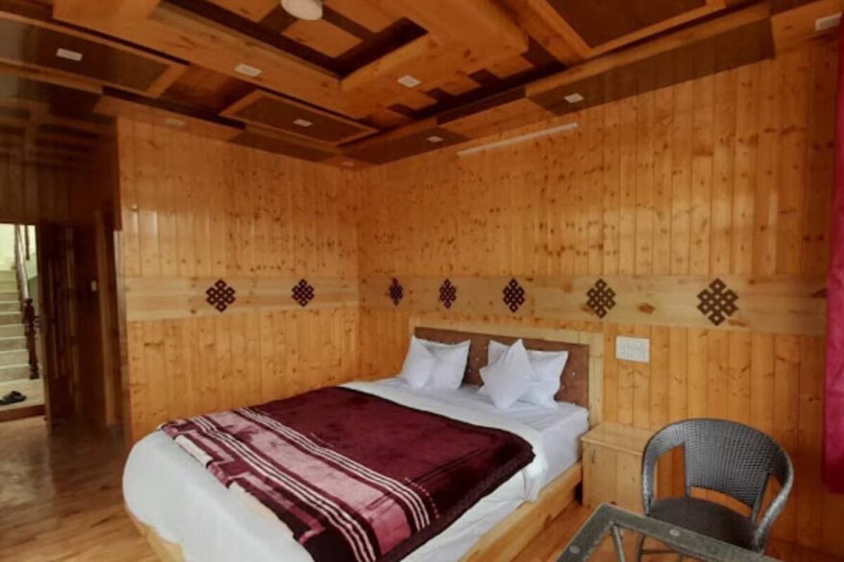 A wooden cabin room with a bed, a chair, and a window.