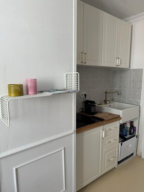 Kitchen area features a white cabinetry, tiled backsplash, and wooden countertop with a kettle and cutting board.