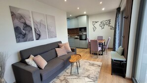Un salon moderne avec un canapé gris, une table basse et un coin repas comprenant une table et des chaises en bois.