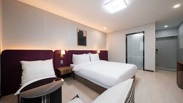Una habitación de hotel moderna con una cama grande, un escritorio y una silla. Hay una mesita pequeña y un estante fijado a la pared.