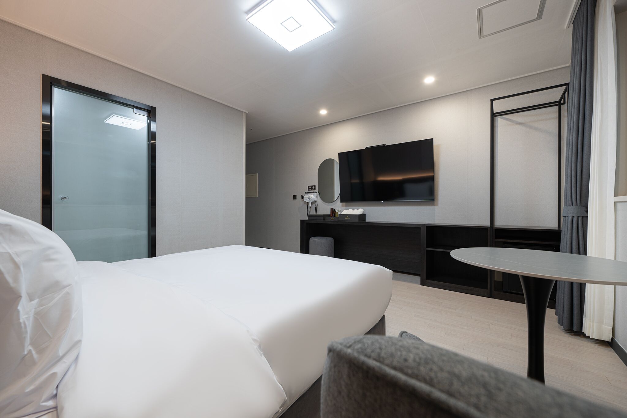Una habitación de hotel moderna con una cama, un escritorio, un televisor de pantalla plana y una mesita.